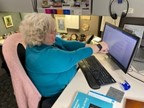 A person sitting at a desk with a computer  Description automatically generated with low confidence