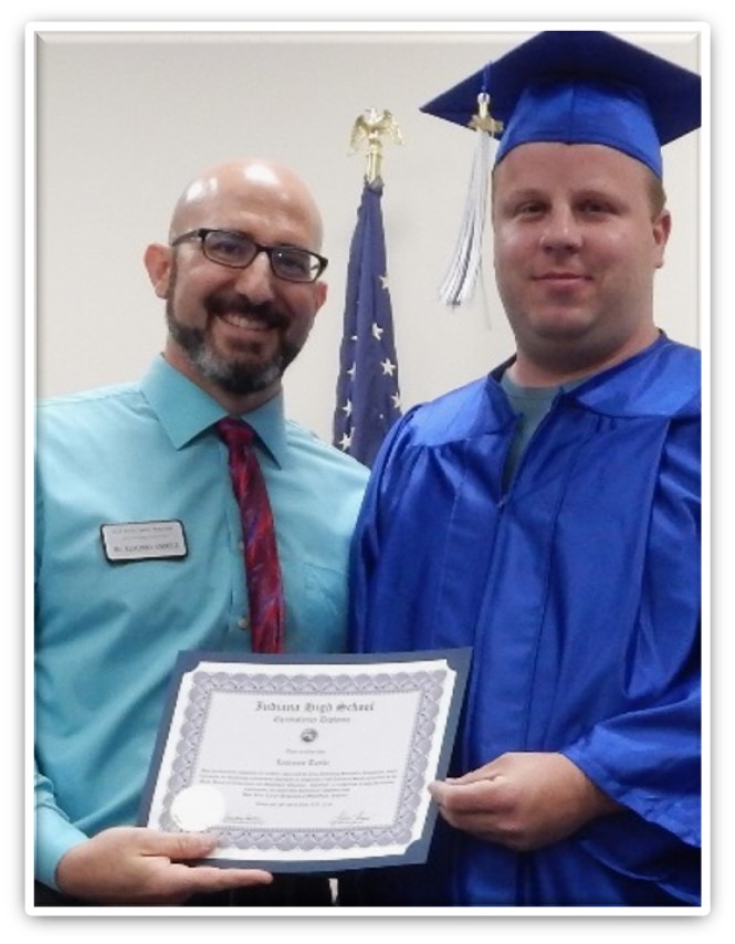 Image of a student standing in front of a chalkboard with Indiana High School Equivalency written on it and a graduation cap drawn around her head 