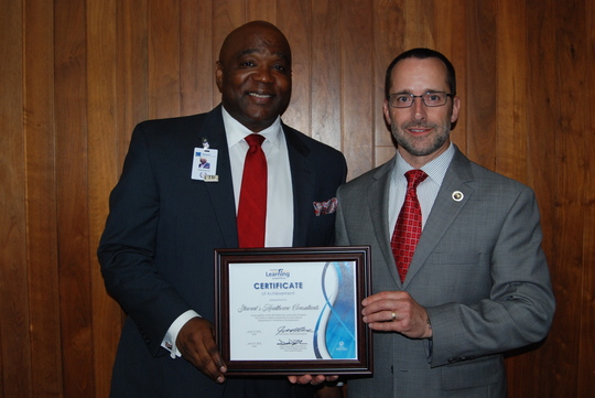 Darrel Zeck and representative from Stewart's Healthcare Consultants holding SEAL