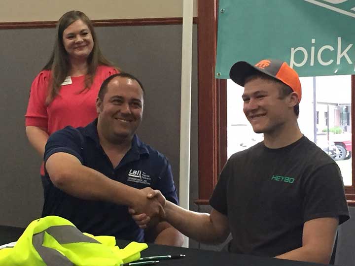 Picture of Employer Shaking the hand of a high school Student who is signing on with that employer
