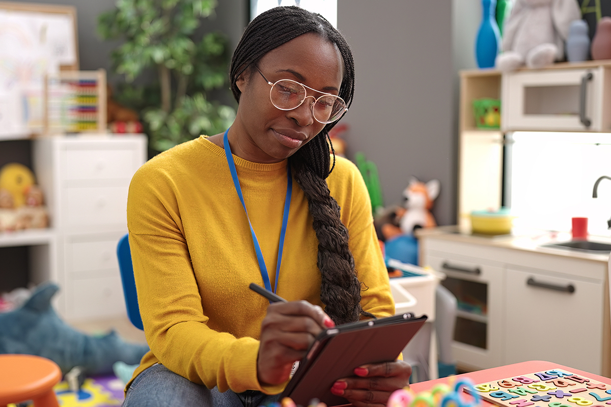 A day care worker inputs information on her tablet.