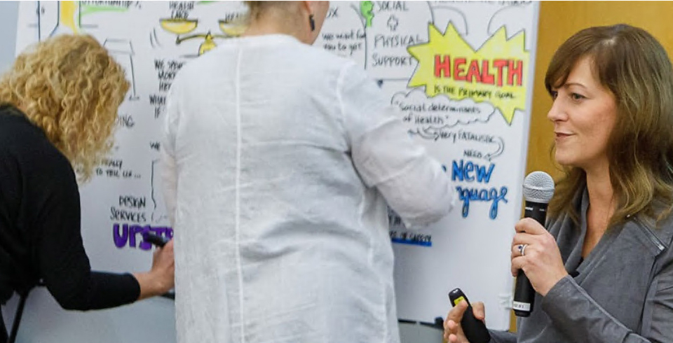 The artists work on creating on the board as Jen gives her speech.