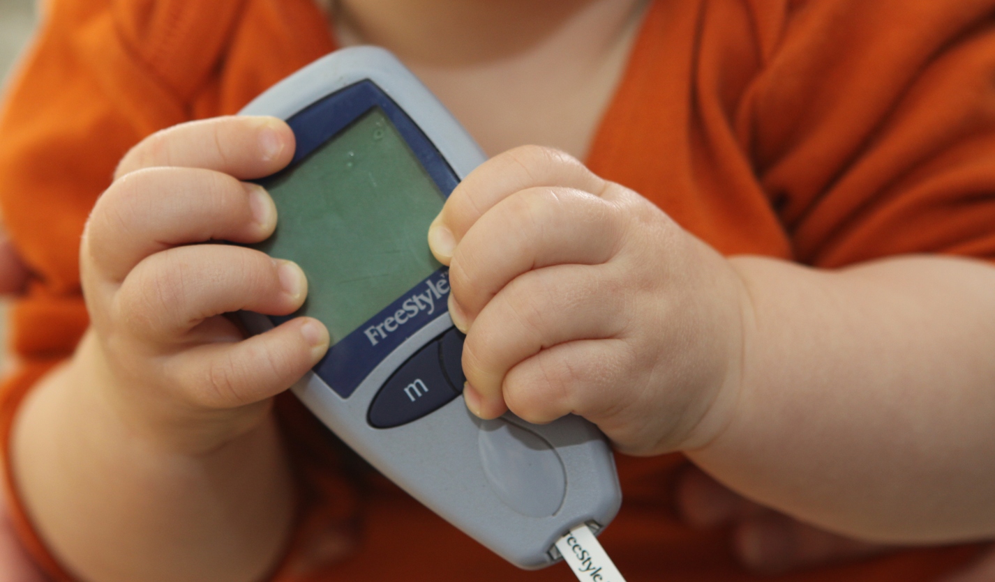 baby hands holding diabetes monitor