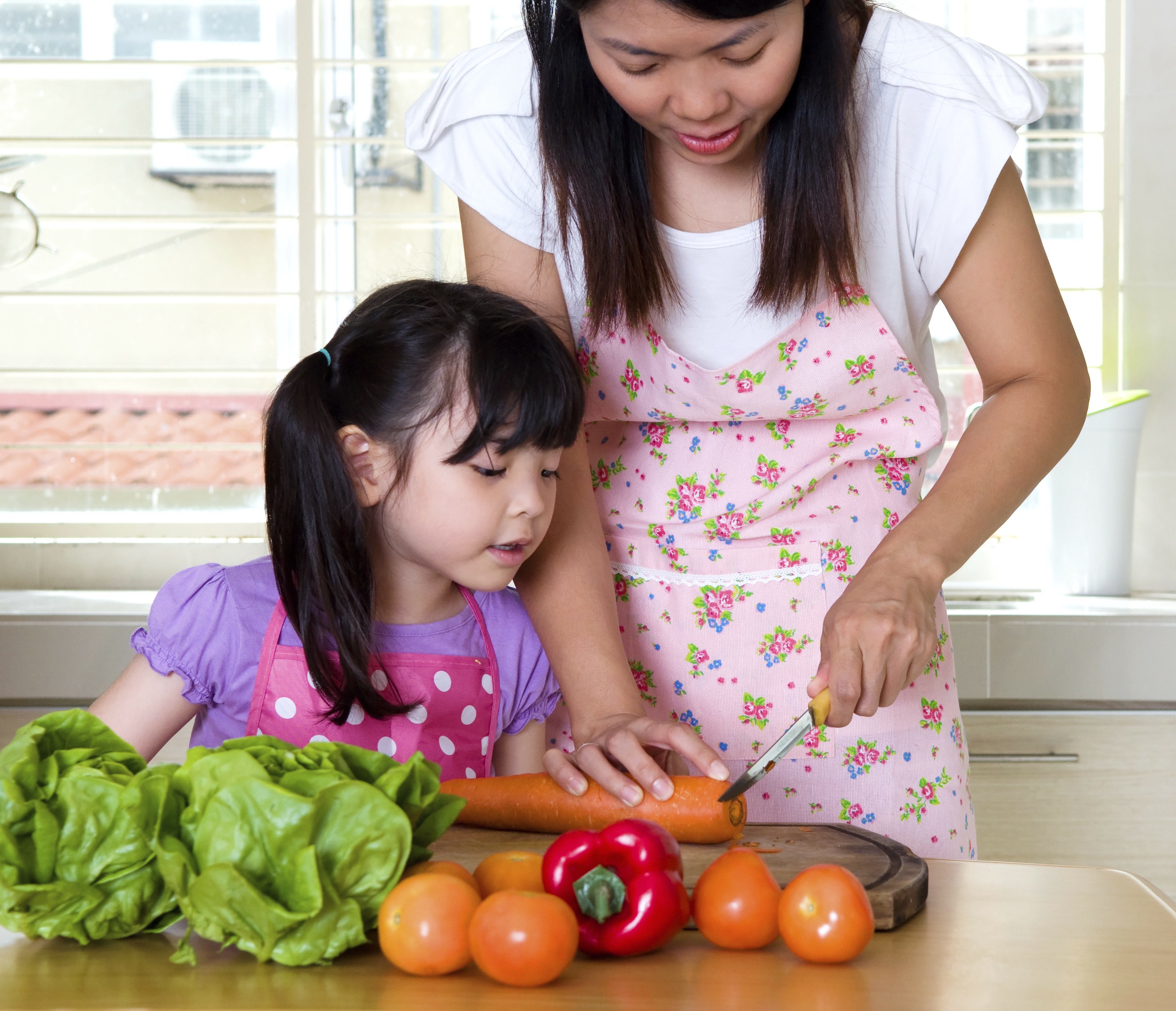 mom cutting up vegetables with child