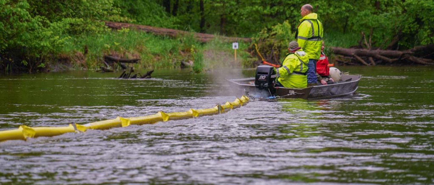 image of emergency response staff setting out a boom on water