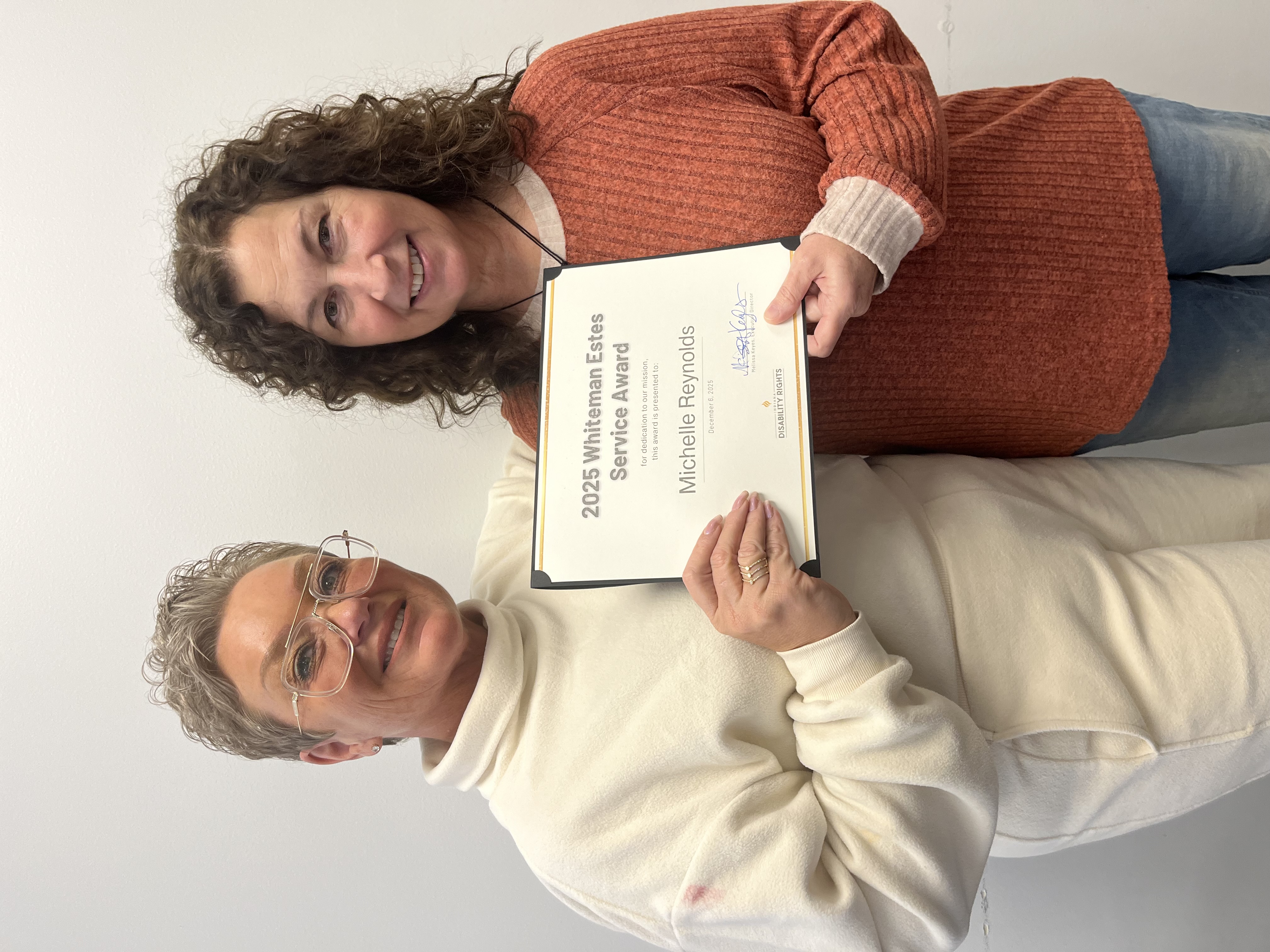 Two women smiling, holding a paper certificate between them