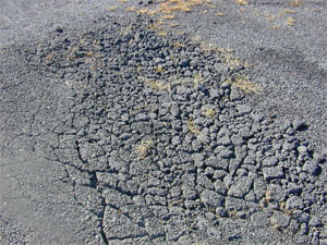 Photo showing a small area of high-severity alligator cracking where the cracks are                 well defined and spalled, and many of the small pieces between the cracks appear loose (i.e., a FOD potential).