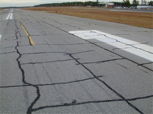 Overview photo of a runway showing block cracking over a large area of the runway surface.           The block cracking is noticeable on the pavement as a pattern of rectangular pieces of pavement where the visible longitudinal and transverse cracks have defined the borders of the           pavement rectangles. The majority of the cracks in the photo have been sealed.