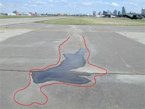 Photo showing a low-severity depression with standing water in it.           A red line has been drawn on the photo to outline the area with the depression.
