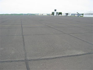 Overview photo of an apron pavement with a uniform rectangular pattern of low-severity           transverse and longitudinal cracks. The pattern is the result of cracks that have reflected through the asphalt surface at the joints of the PCC slabs below.