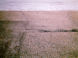 Overview photo showing some signs of slippage cracking, but no visible cracks yet.            In the photo, cut grooves in the pavement surface have noticeably warped due to turning wheels or braking.