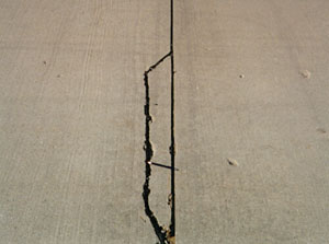 Close-up photo of a low-severity joint spall. The spall is a fairly long but narrow spall, and is defined by a single medium-severity crack.