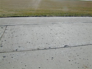 Overview photo of a PCC pavement with widespread popouts. The popouts are visible in the photo as           'holes' in the surface where individual pieces of aggregate have come loose from the pavement's surface.