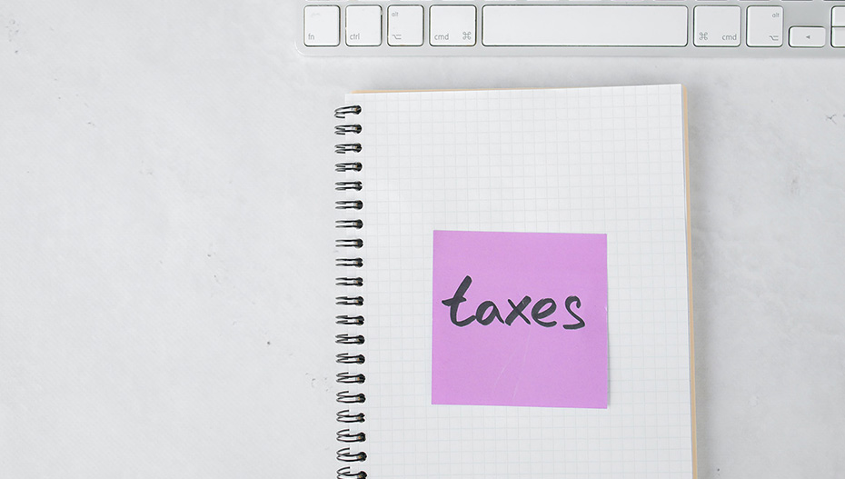 white desk with open notebook showing post-it labeled taxes