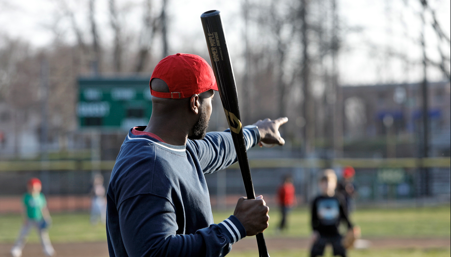 Man coaching little league baseball