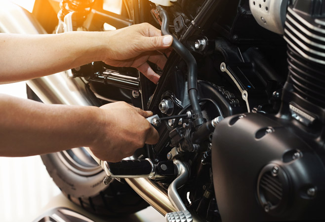 Person tightening a screw on the side of their motorcycle.