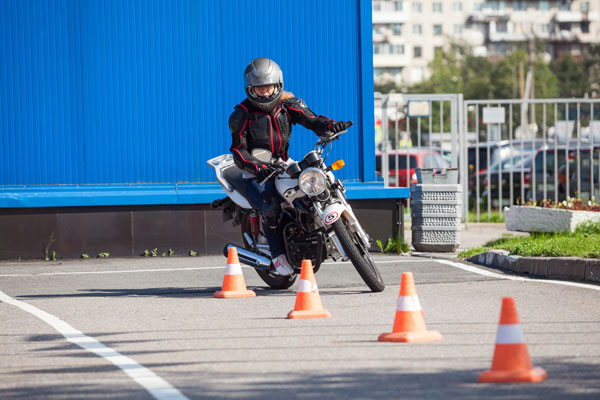 Motorcycle rider learning to weave between cones.