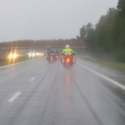 Motorcycles riding on the highway in the rain.
