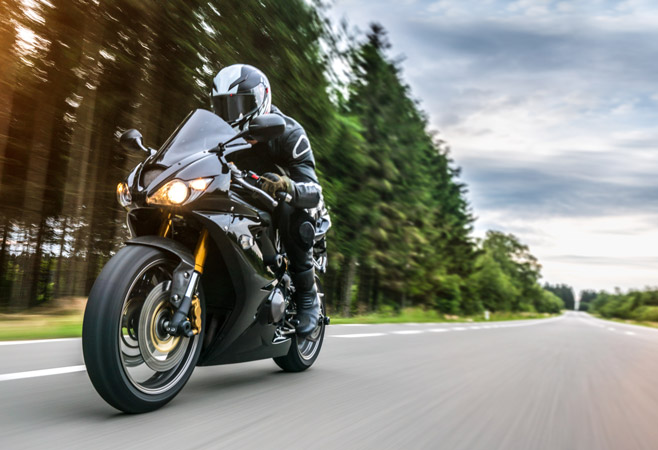 Motorcycle rider speeding down a highway toward the camera