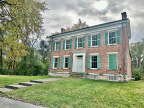 A brick house with green shuttersDescription automatically generated