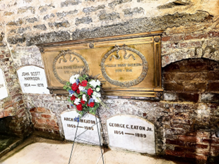 A tombstones and flowers on a stone wallDescription automatically generated